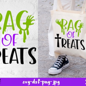 Op de afbeelding: Een witte tote bag met een zwart en groen ontwerp met de tekst "Bag of Treats" met een kruis en druppelende groene handen. De tas wordt vastgehouden door een persoon die een witte broek en zwarte schoenen draagt.
