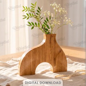 K&ouml;nnte beinhalten: Eine Holzvase mit bogenf&ouml;rmigem Sockel und schmalem Hals, die Gr&uuml;n und kleine wei&szlig;e Bl&uuml;ten enth&auml;lt. Die Vase besteht aus hellbraunem Holz und steht auf einem Tisch mit einem wei&szlig;en Tuch. Das Bild enth&auml;lt auch den Text "Digital Download".