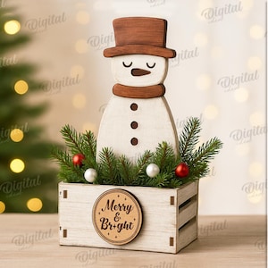 May include: A wooden snowman decoration with a brown top hat and scarf, set in a white wooden crate filled with greenery and red and white ornaments. The crate has a circular sign that reads "Merry & Bright".