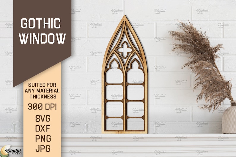 May include: A wooden cutout of a gothic window with a pointed arch and multiple panes. The window is on a white brick wall with a dried grass plant in a white vase.