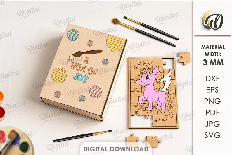 May include: A wooden jigsaw puzzle with a pink unicorn design, and a box with the text "A BOX OF JOY". The box is decorated with colorful circles and a paintbrush. Two paintbrushes are also visible.