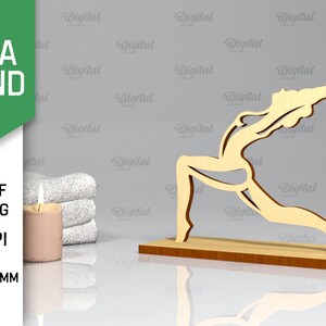 Peut inclure: Support de yoga en bois avec une d&eacute;coupe d'une personne en position de yoga. Le support a une &eacute;paisseur de 3 mm et est pr&eacute;sent&eacute; sur une surface gris clair avec une bougie et des serviettes.