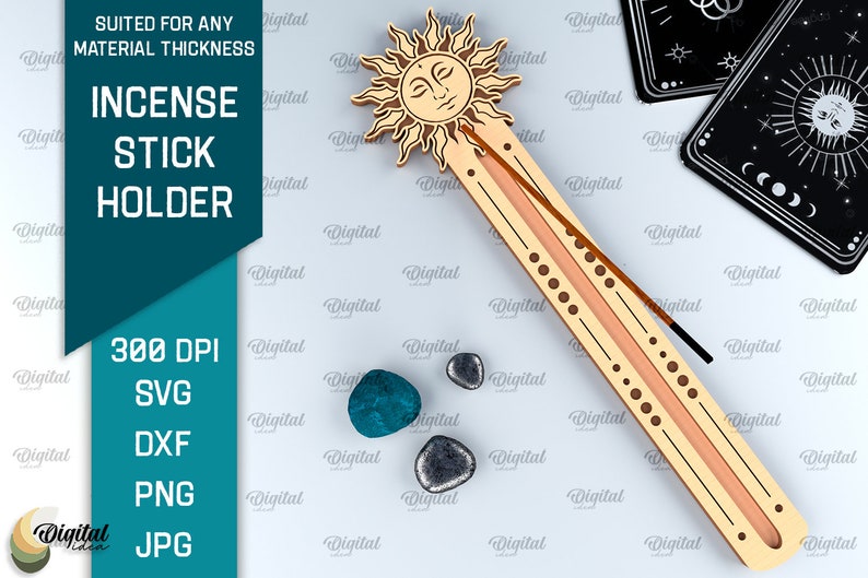 May include: A wooden incense stick holder with a sun design. The holder is light brown with a peach colored groove for the incense stick. The sun has a face and rays. The holder is on a white background with small blue and gray stones.