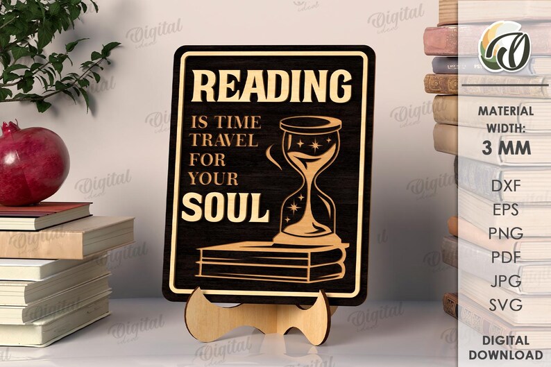 K&ouml;nnte beinhalten: Schwarzes Holzschild mit dem Text "READING IS TIME TRAVEL FOR YOUR SOUL" und einer Sanduhr-Illustration. Das Schild wird auf einem Holzst&auml;nder pr&auml;sentiert. Die Breite des Schildes betr&auml;gt 3 mm. Ein Stapel B&uuml;cher und ein Granatapfel sind im Hintergrund.