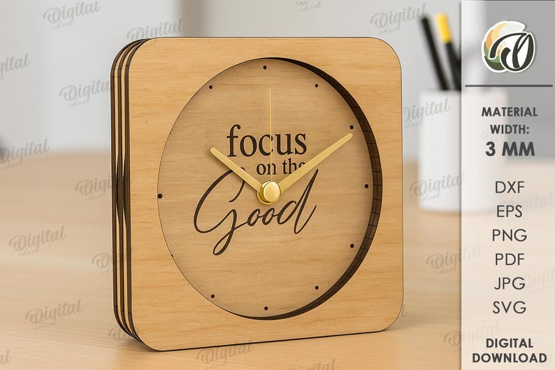 K&ouml;nnte beinhalten: Eine quadratische Holzuhr mit hellbraunem Finish. Das Zifferblatt zeigt die Worte "focus on the Good" in einer Schriftart. Die Uhrzeiger sind goldfarben.