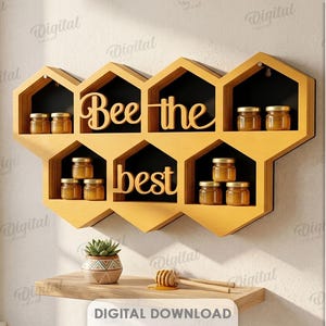 Op de afbeelding: Een geel, honingraatvormig wandrek met zwarte achterwanden, voorzien van de uitgesneden tekst "Bee the best" in een schrijflettertype. Het rek bevat diverse kleine glazen potjes gevuld met honing, verdeeld over de zeshoekige vakken.