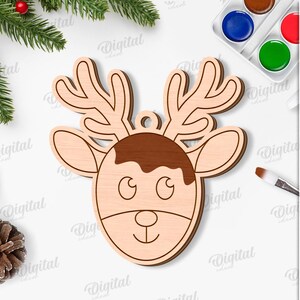 May include: A wooden reindeer head ornament with a light brown face and antlers, and a darker brown section on top. The ornament has a small hole for hanging. The image also includes text that says "SUITED FOR ANY MATERIAL THICKNESS" and "DIGITAL DOWNLOAD".