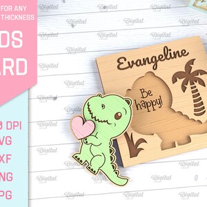 May include: A wooden card with a green dinosaur holding a pink heart. The card says "Evangeline" and "Be happy!" in a brown font.