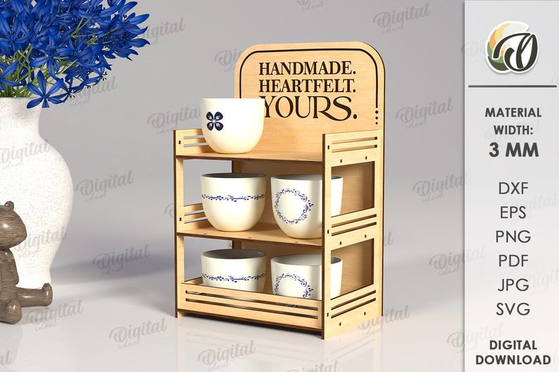 May include: A wooden display shelf with three levels, holding several white ceramic cups with blue floral designs. The top of the shelf has the words "HANDMADE. HEARTFELT. YOURS." etched into the wood.