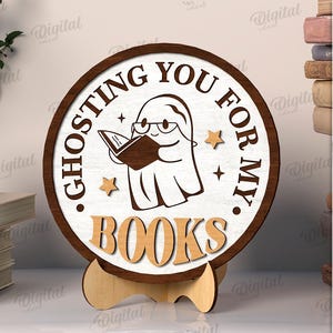 K&ouml;nnte beinhalten: Runder Holzschild mit dem Text "Ghosting You For My Books" und einem Cartoon-Geist, der ein Buch liest. Das Schild wird von einem Holzst&auml;nder getragen. Die Materialbreite betr&auml;gt 3 mm.