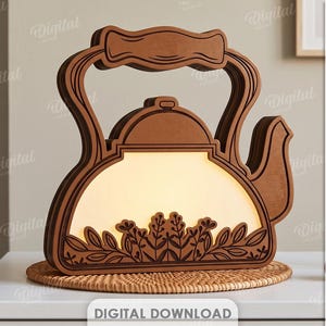 Puede incluir: Una lámpara de tetera de madera en capas con un centro de luz cálida y un diseño floral recortado en la base. La estructura presenta un asa y un pico, con texto en el lateral que enumera formatos de archivo: RECOMMENDED MATERIAL: FROM 6MM, DXF, EPS, PNG, PDF, JPG, SVG.