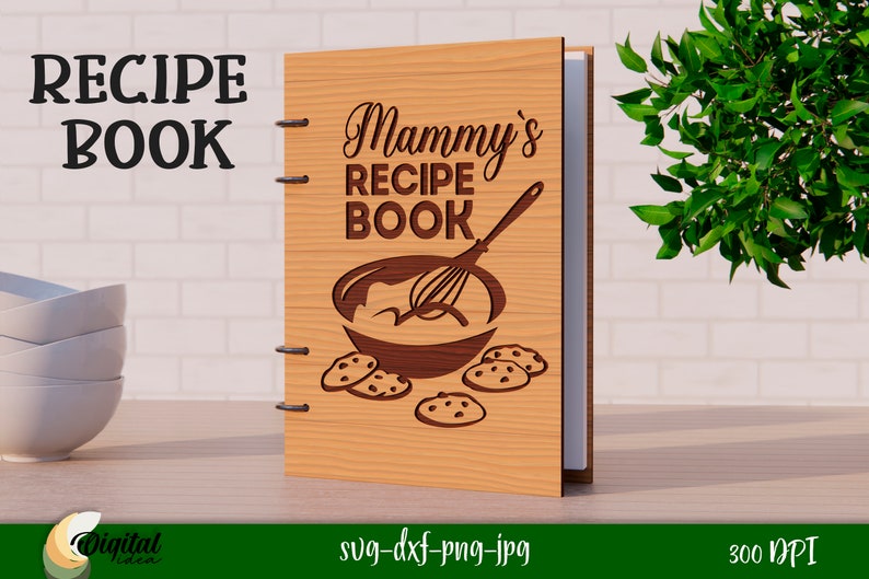 Może przedstawiać: Drewniana okładka książki kucharskiej z tekstem "Mammy's Recipe Book" i grafiką miski do mieszania z trzepaczką i ciasteczkami.