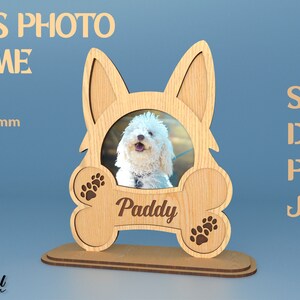 Puede incluir: Un marco de fotos de madera para mascotas con forma de hueso de perro con huellas de patas. El marco está diseñado para contener una foto de 7,6 cm y tiene espacio para un nombre. El nombre "Paddy" está grabado en el marco. El marco está hecho de un material de 3 mm de grosor y tiene una resolución de 300 DPI.