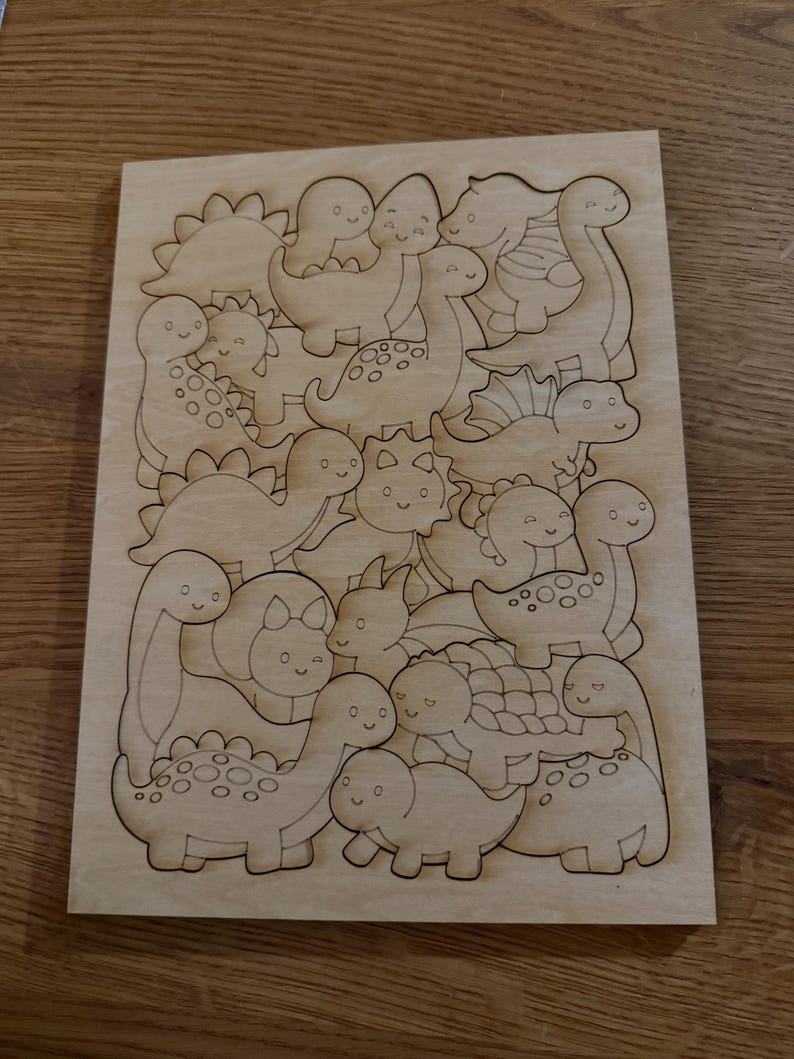 Puede incluir: Una tabla rectangular de madera clara con contornos de dinosaurios de dibujos animados grabados con l&aacute;ser. El dise&ntilde;o incluye varias especies con caras sonrientes, manchas y caparazones texturizados, dispuestos en un patr&oacute;n denso y superpuesto.