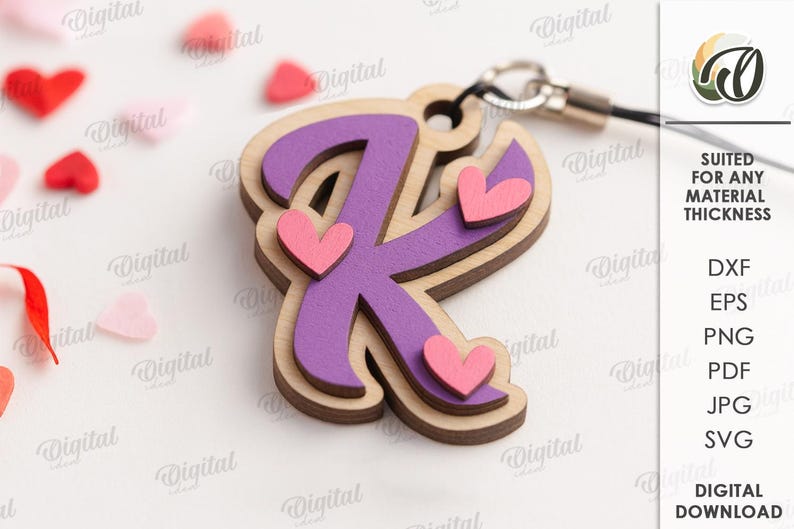 May include: A layered wooden letter "K" charm with a purple center and pink hearts. The charm is attached to a silver-colored clasp. The image also includes scattered heart-shaped confetti and the text "SUITED FOR ANY MATERIAL THICKNESS".