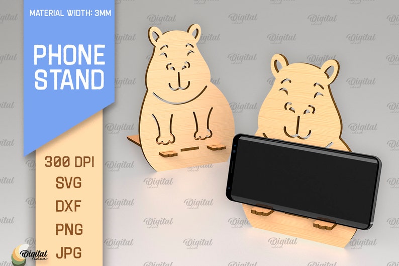 May include: A phone stand made of wood, shaped like a cartoon animal with a smiling face. The stand is designed to hold a smartphone upright. The text "PHONE STAND" is visible in the image.