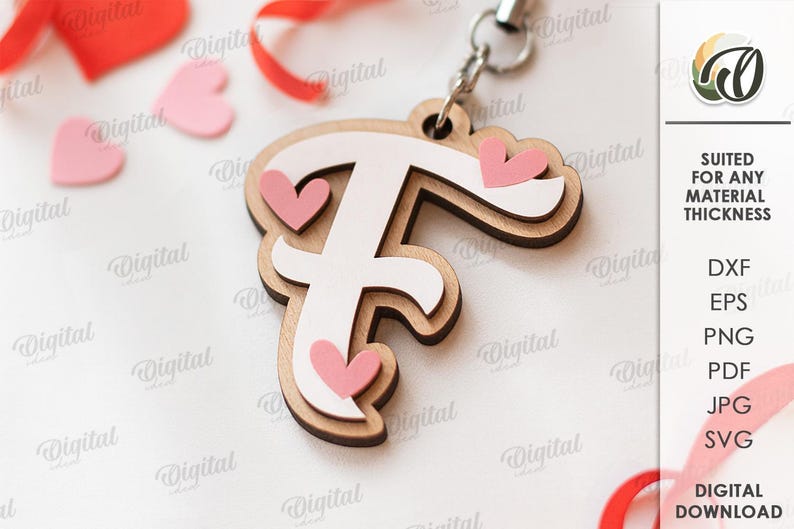May include: Wooden letter "F" keychain with a white center and pink heart accents. The keychain is layered with a light brown wood and includes a silver-colored metal ring. The image also includes pink heart shapes and red ribbon.