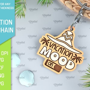 May include: A wooden keychain with a brown and white design. The keychain features a sun hat with palm trees and the text "Vacation Mood On".