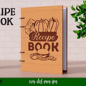 Może przedstawiać: Drewniana książka kucharska z brązową okładką i wzorem warzyw, hamburgera i tekstem "Recipe Book".