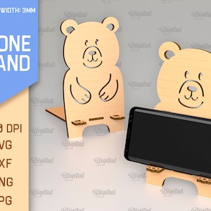 May include: A phone stand made of wood with a bear design. The stand is 3mm thick and is available in SVG, DXF, PNG, and JPG formats. The stand is designed to hold a phone upright.
