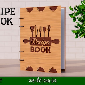 Może przedstawiać: Drewniana książka kucharska z brązowym wałkiem do ciasta i przyborami kuchennymi. Książka ma tytuł "Recipe Book".