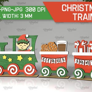 May include: A Christmas train set with three cars. The first car is green and features an elf. The second car is red and says "Claus". The third car is red and says "Santa".