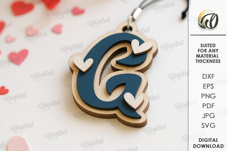 May include: Wooden layered letter "G" pendant in navy blue and natural wood tones, adorned with three small white hearts. The pendant hangs from a black cord. The image also includes the text "SUITED FOR ANY MATERIAL THICKNESS".