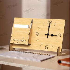 K&ouml;nnte beinhalten: Eine Holz-Schreibtischuhr mit Stifthalter und dem Text "Time to relax". Die Uhr hat schwarze Zeiger und ein minimalistisches Design. Ein Notizblock und ein Stift sind ebenfalls sichtbar.