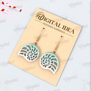 May include: A pair of wooden earrings shaped like seashells with a blue and white gradient design. The earrings are displayed on a card with the text "Digital Idea - Wooden Earrings".