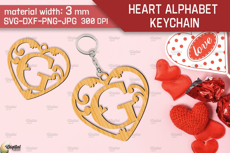 May include: A wooden heart-shaped keychain with a decorative letter G inside. The keychain is made of light brown wood and has a silver metal ring. The background is pink with red hearts and other Valentine's Day decorations.