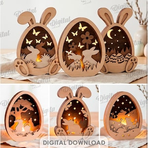 Può includere: Una collezione di dieci design in legno a tema pasquale, tra cui forme di coniglietti e uova, adatti a vari spessori di materiale. I design presentano sagome ritagliate di coniglietti, farfalle e stelle, con un bagliore caldo dall'interno. La scritta "DOWNLOAD DIGITALE" è visibile.