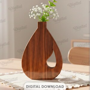 K&ouml;nnte beinhalten: Eine braune Holzvase mit Tropfendesign und Aussparung, gef&uuml;llt mit wei&szlig;en Blumen. Die Vase hat eine satte braune Farbe und steht auf einem cremefarbenen Platzset. Der Text "DIGITALER DOWNLOAD" ist ebenfalls enthalten.