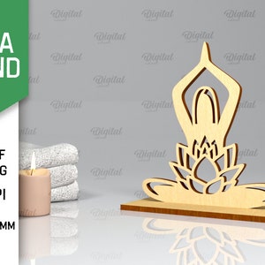 Peut inclure: Un support de yoga en bois avec une d&eacute;coupe repr&eacute;sentant une personne en position de yoga assise sur une fleur de lotus. Le support a une &eacute;paisseur de 3 mm et convient &agrave; la d&eacute;coupe au laser.