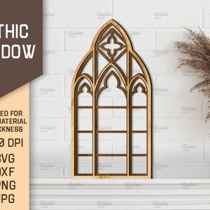 May include: A wooden cutout of a gothic window with a pointed arch and multiple panes. The window is on a white brick wall with a dried grass plant in a white vase.