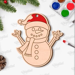 May include: A wooden snowman ornament with a red hat and scarf. The snowman has a smiling face with button eyes and a carrot nose. The ornament is surrounded by Christmas decorations and the text "SUITED FOR ANY MATERIAL THICKNESS".