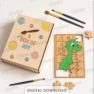 May include: A wooden box with the text "A BOX OF JOY" and a cartoon dragon puzzle. The box has colorful circles and a paintbrush design. Paintbrushes and a palette are also visible. The puzzle is 3 mm wide.