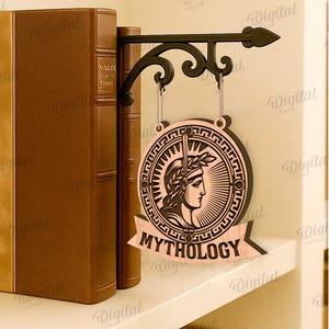 Peut inclure: Un panneau d&eacute;coratif pour une &eacute;tag&egrave;re, avec un motif circulaire repr&eacute;sentant un profil de personne portant une couronne de laurier et le mot "MYTHOLOGY". Le panneau est suspendu &agrave; un support en m&eacute;tal noir, &agrave; c&ocirc;t&eacute; de deux livres bruns.