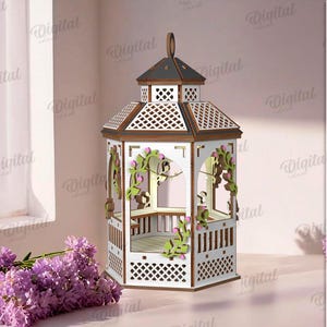 May include: A laser-cut wooden gazebo with a white body, brown trim, and a dark gray roof. The gazebo is decorated with green and pink floral accents. The image also includes a bouquet of purple flowers and text that says "MATERIAL WIDTH: 3 MM".
