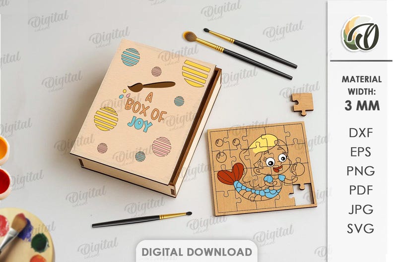 May include: A wooden box with the text "A Box of Joy" and a mermaid puzzle. The box is decorated with colourful circles and a paintbrush icon. Two makeup brushes and a palette are also visible.