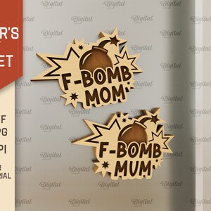 Może przedstawiać: Dwa drewniane wycięcia bomby z tekstem "F-Bomb Mom" i "F-Bomb Mum" w stylu komiksowym. Wycięcia znajdują się na jasnoszarym tle.