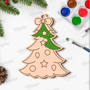 May include: Wooden Christmas tree ornament with a green painted top section, bow, and star details. The image includes paint supplies, pine needles, and the text "SUITED FOR ANY MATERIAL THICKNESS".