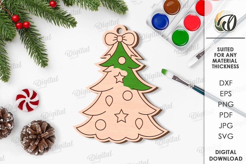 May include: Wooden Christmas tree ornament with a green painted top section, bow, and star details. The image includes paint supplies, pine needles, and the text "SUITED FOR ANY MATERIAL THICKNESS".