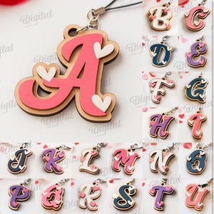 Puede incluir: Una colección de 26 diseños de letras de madera, cada uno con un acento de corazón, en varios colores. Las letras son adecuadas para diferentes grosores de material. La imagen también incluye el texto "26 DESIGNS" y "DIGITAL DOWNLOAD".