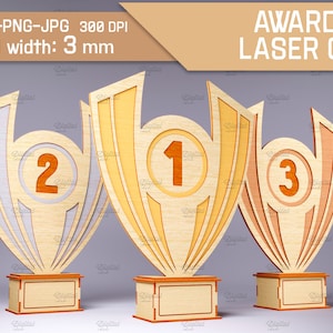 Può includere: Tre trofei in legno per premi con finitura dorata, bianca e marrone. I trofei hanno la forma di coppe e riportano i numeri 1, 2 e 3. I trofei sono spessi 3 mm e sono progettati per il taglio laser.