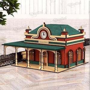 以下が含まれることがあります： 赤色のファサードと緑色の屋根を持つ鉄道駅の詳細な木製モデル。モデルには時計塔と「Railway Station」の文字が含まれています。ミニチュア列車が線路にあります。材料の幅は3mmです。