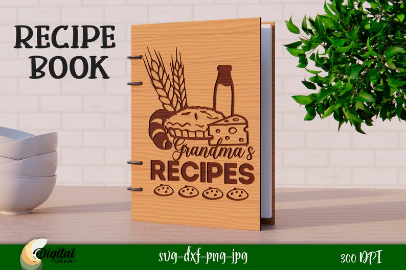 Może przedstawiać: Drewniana książka kucharska z tekstem "RECIPE BOOK" i "Grandma's RECIPES" na okładce. Okładka zawiera r&oacute;wnież ciasto, butelkę mleka, chleb, ser i kłosy pszenicy.