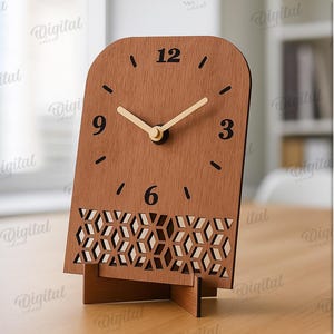 K&ouml;nnte beinhalten: Eine Holz-Schreibtischuhr mit hellbraunem Finish. Das Zifferblatt hat schwarze Ziffern und Zeiger mit einem dekorativen geometrischen Muster am Sockel. Die Uhr ist 3 mm breit.