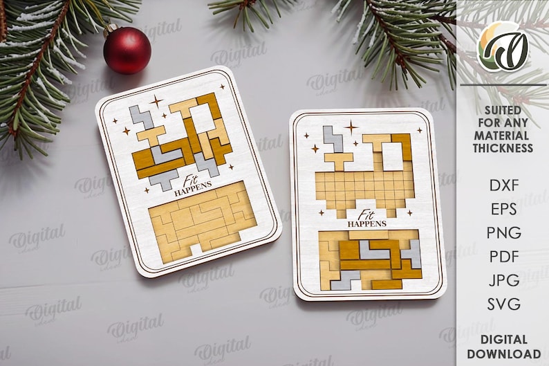 May include: Two wooden puzzle pieces with a light wood finish, featuring geometric shapes in gold and gray. The phrase "Fit Happens" is printed on each piece. A red ornament and evergreen branches are in the background.