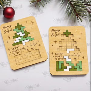 May include: Two wooden Christmas tree puzzles with the text "Merry & Bright" and "Let's Make It Fit!". The trees are made of green and white geometric shapes. A red ornament and pine branches are in the background.