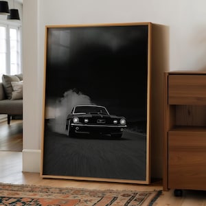 Pode incluir: Impressão emoldurada em preto e branco de um carro esportivo preto clássico derrapando em uma estrada. O carro é o ponto focal, com fumaça saindo dos pneus. A imagem é definida em um fundo escuro.